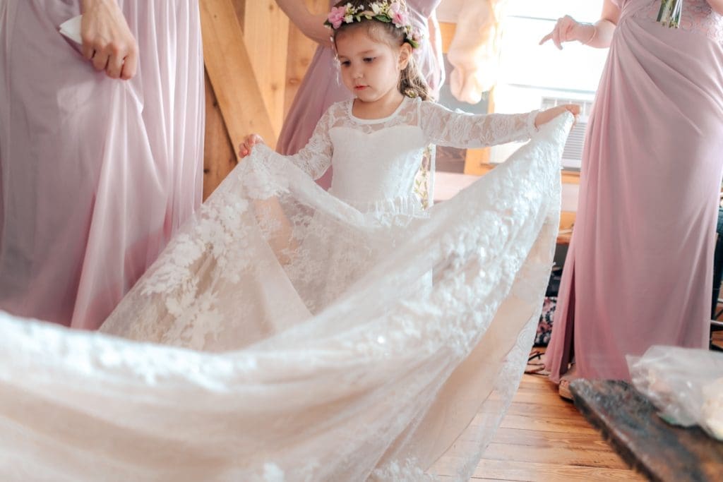Flower girl holding dress in bridal suite at Knotted Roots on the Lake