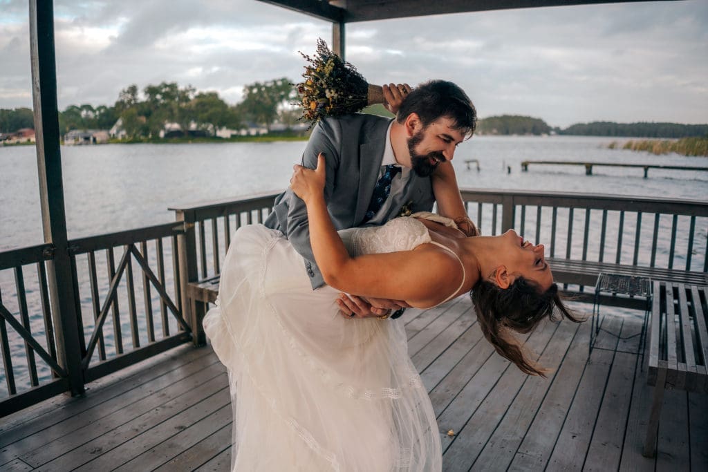 Groom dipping bride on dock at Knotted Roots on the Lake - Land O' Lakes