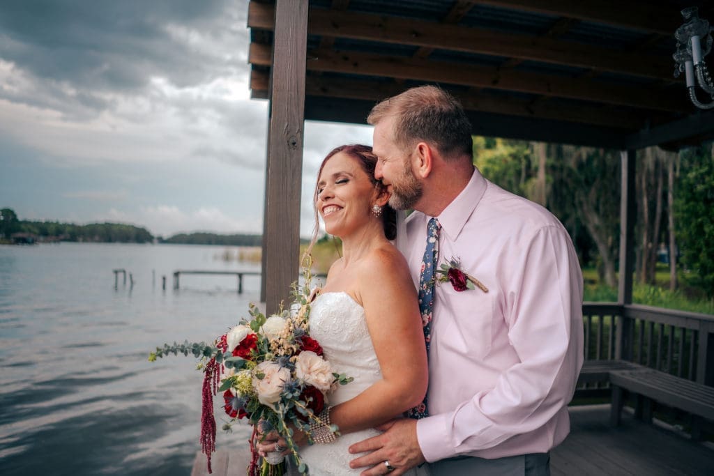 Bride and groom smiling on dock at Knotted Roots on the Lake - Land O' Lakes