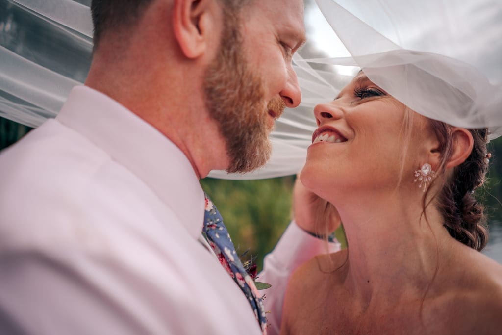 Bride and groom under veil at Knotted Roots on the Lake - Land O' Lakes