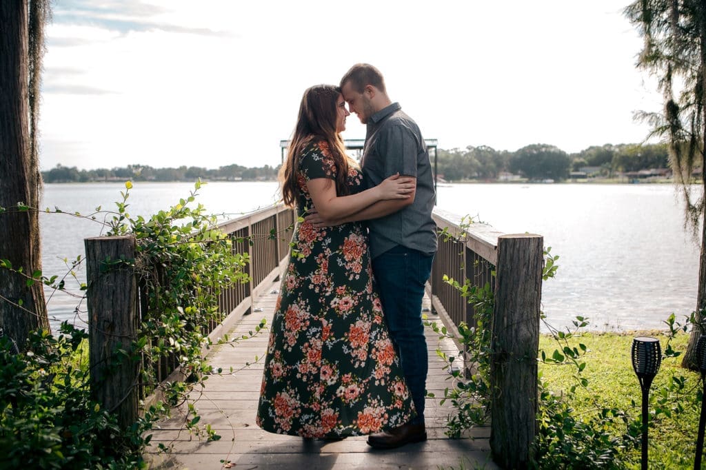Engaged couple touching foreheads on dock at Knotted Roots on the Lake