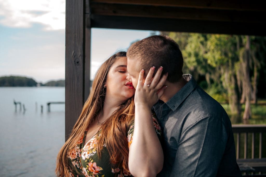 Engaged couple kissing on dock at Knotted Roots on the Lake
